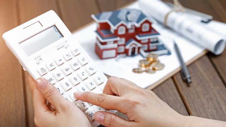 A female hand operating a calculator in front of a Villa house model